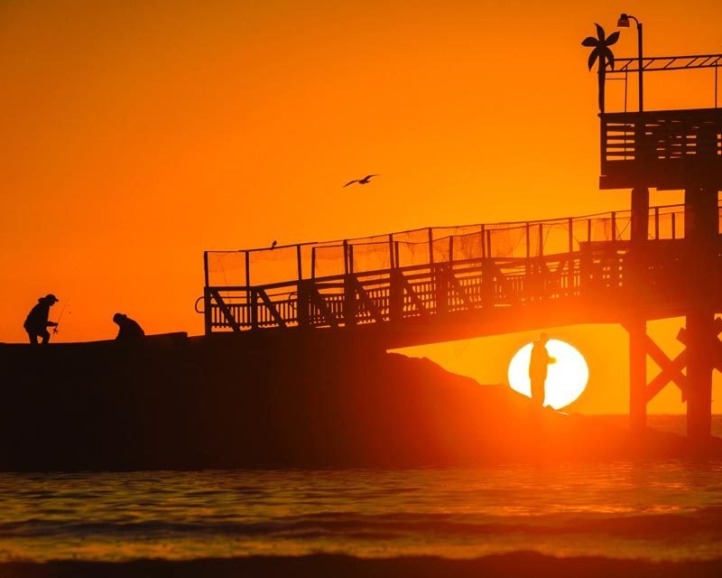 Anglers on the jetty in front of the sunrise at the 61st Street Fishing Pier